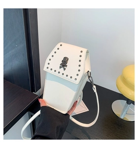 Detailed view of white coffin-shaped crossbody bag with black rivets and skull motif