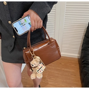 Détail d'un sac Boston vintage en cuir PU marron avec un joli accessoire de charme ours