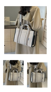 Detail of canvas tote bag with striped straps, leather trim, and adjustable shoulder strap
