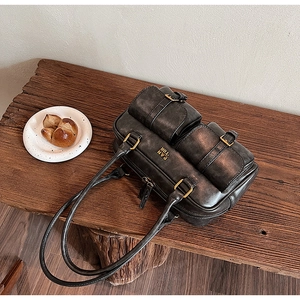 Macro detail of retro bowling bag with matte gold hardware and textured leather finish