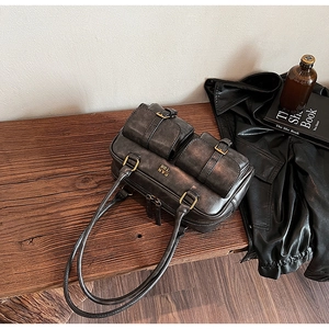 Detail of dark grey retro bowling bag with double front pockets on wood background
