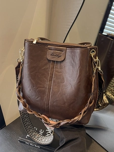 Brown vintage leather bucket bag with wide woven strap and gold hardware accents