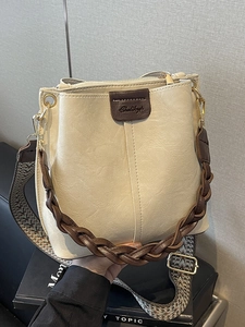 Retro beige bucket bag with vintage leather logo and wide geometric woven shoulder strap