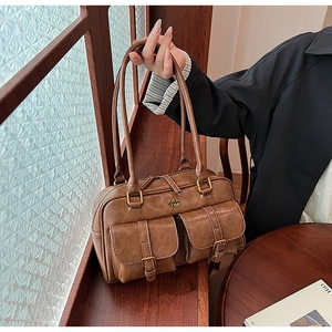 Detailed shot of brown vintage leather bowling bag with twin buckled pockets and metal logo