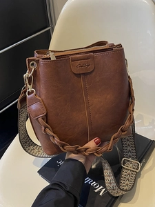 Retro brown leather bucket bag with braided handle and wide ethnic jacquard strap