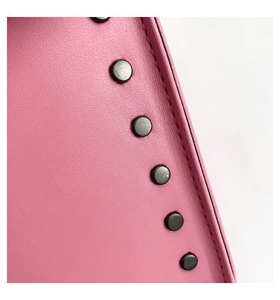 Detailed macro view of pink litchi leather texture with dark nickel rivet studs