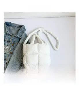 Détail d'un sac matelassé blanc avec une texture douce et une bandoulière amovible