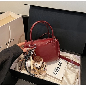 Sac Boston en cuir verni rouge foncé avec breloque en peluche dans un coffret cadeau