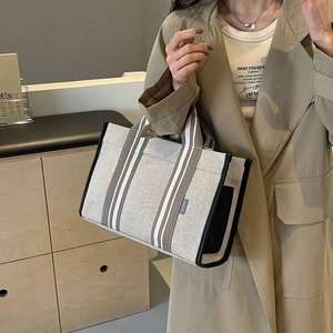 Detail of canvas tote bag showing side branded SJCH tag and black contrast stitching