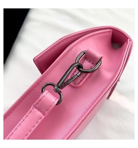 Detailed close-up of pink leather crossbody bag with gunmetal hook and reinforced stitching
