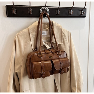 Detailed close-up of brown vintage leather bowling bag with front pockets and long handles