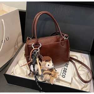 Détail du sac Boston marron avec breloque d'ours en peluche dans un coffret de luxe