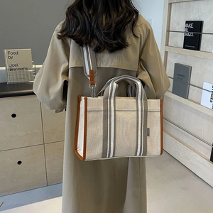 Lifestyle shot of large canvas tote bag with brown leather trim and adjustable strap