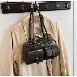 Close-up of black vintage bowling bag with front flap pockets and antique bronze buckles