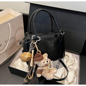 Détail d'un sac à main noir avec breloque ours Duffy dans un coffret cadeau élégant
