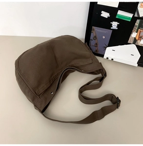 Detail einer braunen Canvas-Umhängetasche mit verstellbarem Gurt in Lifestyle-Szenerie
