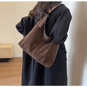 Detail view of large dark brown suede hobo bag showing texture and drape on a shoulder