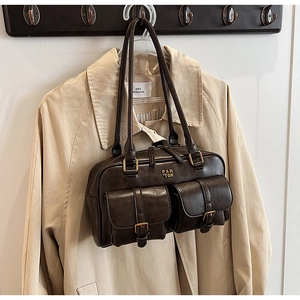 Detail view of dark brown retro leather handbag with dual front pockets and metal logo