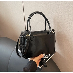 Vue détaillée d'un sac à main noir brillant avec ferrures dorées et poche avant
