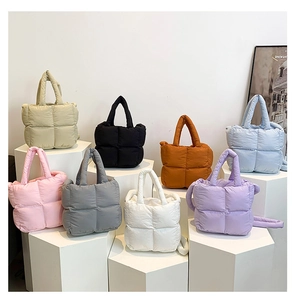 Plusieurs sacs fourre-tout matelassés colorés exposés sur des piliers géométriques