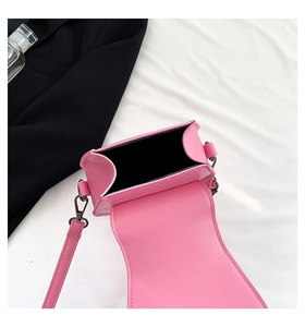 Top view of bright pink mini crossbody bag with black lining and smooth leather texture