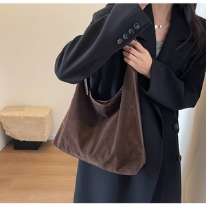 Detail view of the deep brown suede hobo bag's stitching and texture on a model