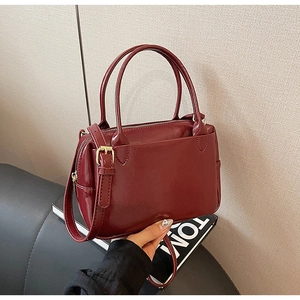 Détail d'un sac à main en cuir bordeaux avec ferrures dorées et bandoulière
