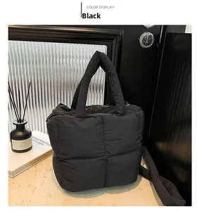 Sac fourre-tout noir matelassé posé sur une surface en marbre dans un décor moderne