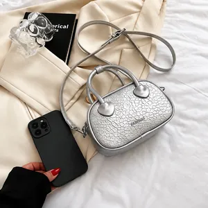 Mini borsa argento a tracolla coccodrillo mostrata con smartphone per scala dimensionale