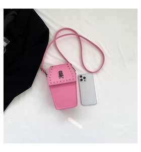 Detail view of pink coffin cross body bag with metal skull and studs showing phone size