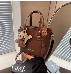 Details der braunen Leder-Eimertasche mit Goldbeschlägen und Bären-Anhänger