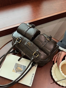 Retro dark brown leather bowling bag with double pockets and gold hardware on wood table
