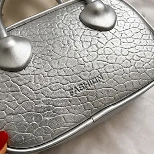 Dettaglio macro della borsa in pelle PU argento con logo FASHION in rilievo
