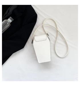 Detail view of a white coffin-shaped crossbody bag with dark metal hardware on a suit background