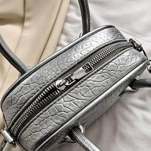 Dettaglio della cerniera in metallo argento e texture a coccodrillo della borsa a mano