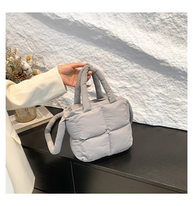 Détail du sac à main matelassé gris avec poignées rembourrées et texture carrée