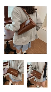 Detail of a brown faux leather baguette bag with gold buckle and adjustable strap