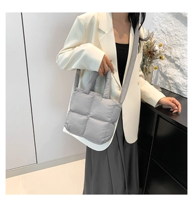 Sac bandoulière matelassé gris porté par un mannequin avec une tenue décontractée
