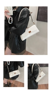 Detail view of cream shoulder bag featuring a vintage brown metallic buckle and leather texture