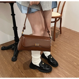 Brown patent leather shoulder bag with gold metal clasp shown in a vintage retro style