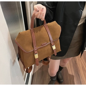Brown faux suede backpack with dark trim and vintage gold buckles held by a model