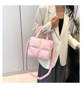 Détail du sac à main rembourré rose clair montrant la texture matelassée et les poignées