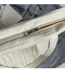 Detail of silver zipper closure on white pleated canvas tote bag with smooth texture