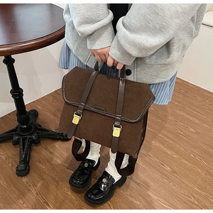 Close-up of brown matte suede messenger bag with gold buckles and white stitching