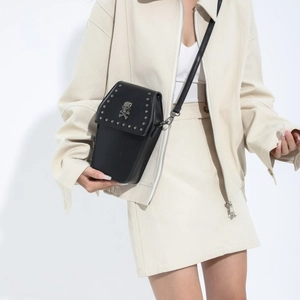 Gothic black coffin-shaped crossbody bag with silver skull stud details on a model