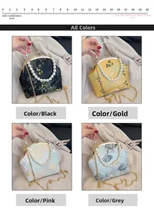Detalle del bolso bordado de fiesta en negro, oro, rosa y gris con asa de perlas