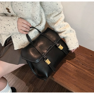 Detailed shot of black vintage leather briefcase with golden metal buckles on wood bench
