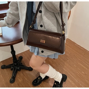 Close-up of a deep brown faux leather baguette bag with a gold rectangular metal buckle