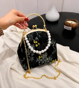 Detalle de bolso bordado chino vintage con asa de perlas y cierre metálico dorado