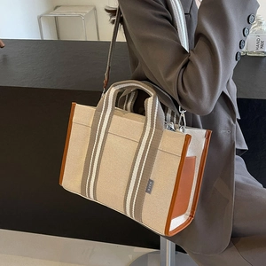 Professional wearing large canvas tote bag with brown leather trim and striped strap